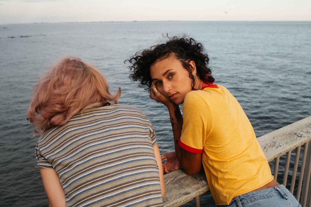 A Young Woman With Curly Hair Looks Directly Into The Camera